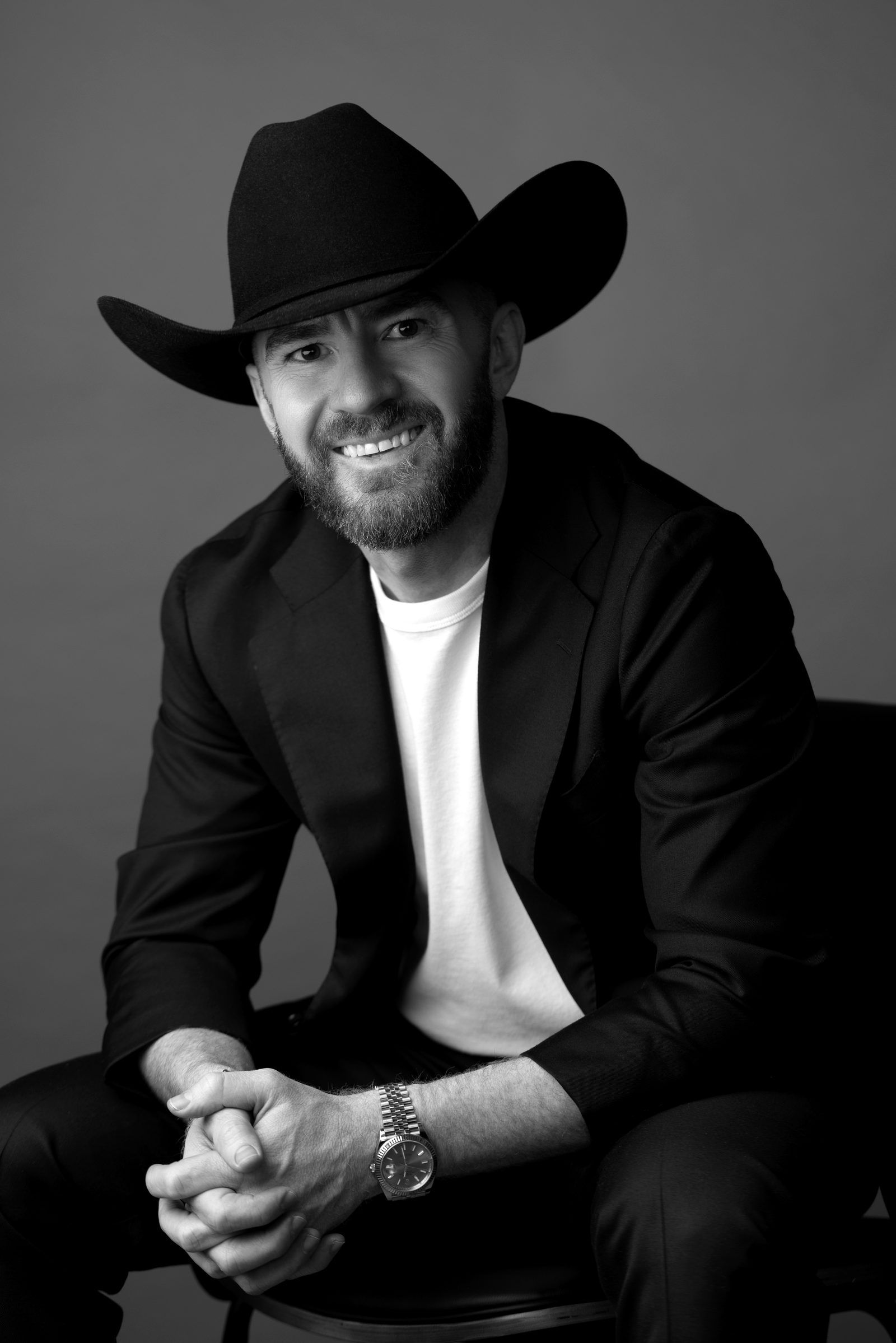 Guy Muller in a black cowboy hat, seated and laughing