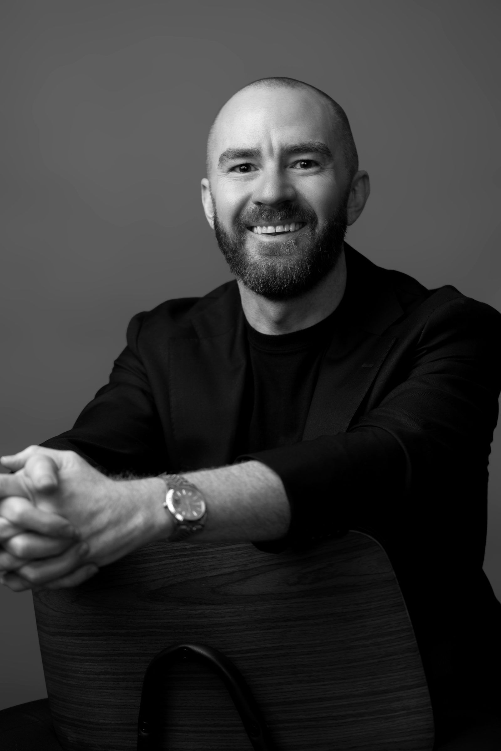 Guy Muller leaning on a chair back, smiling
